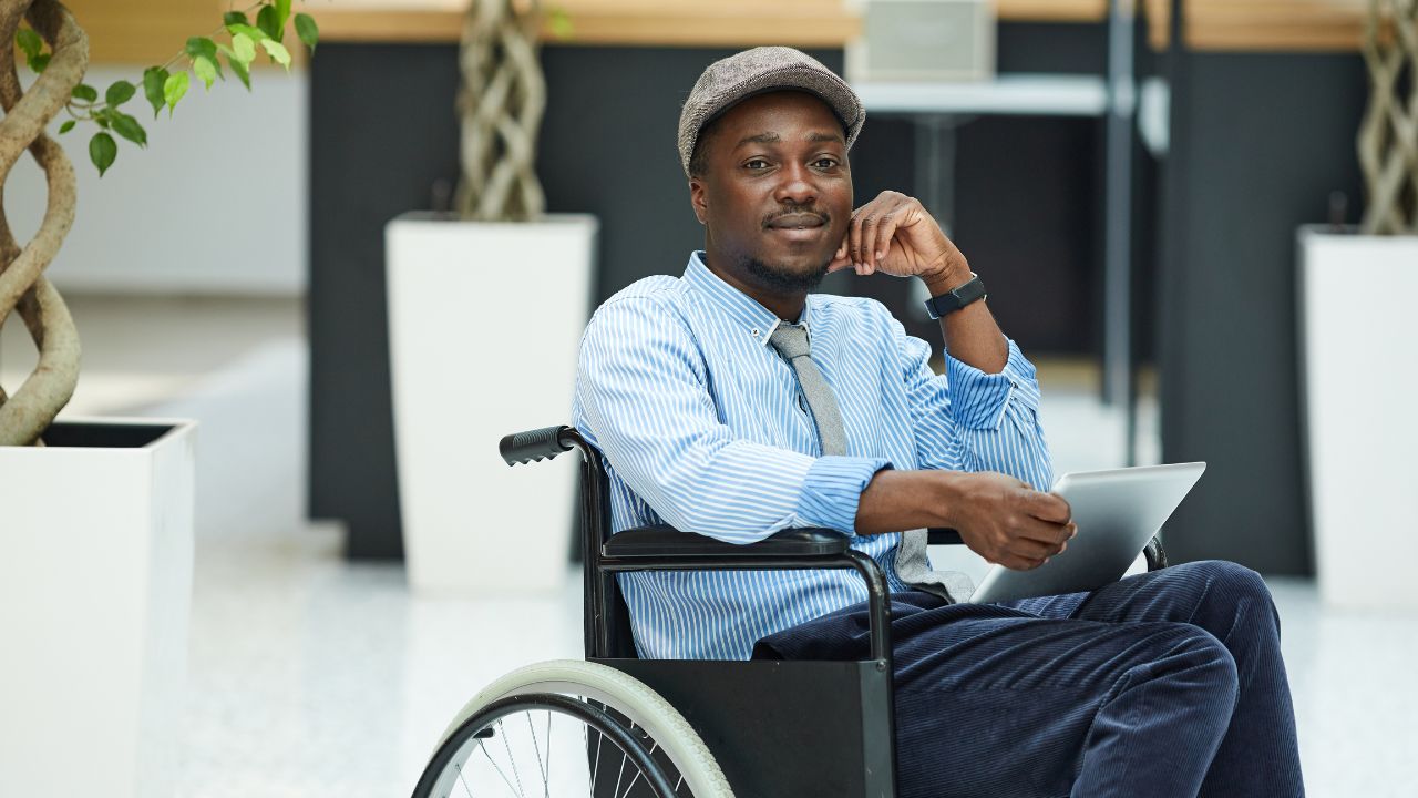 Young African American male in wheelchair holding tablet