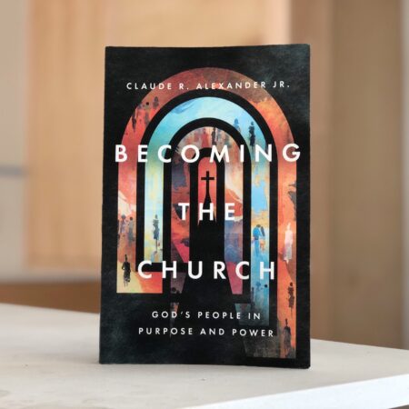 A photograph of the book Becoming the Church by Claude R Alexander Jr propped up on a table